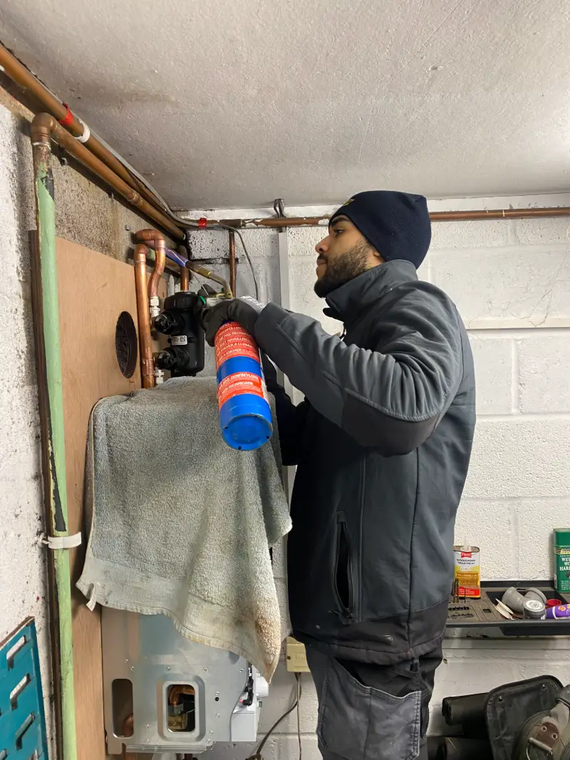 Homely Heating Group engineer working on heating pipework above a boiler